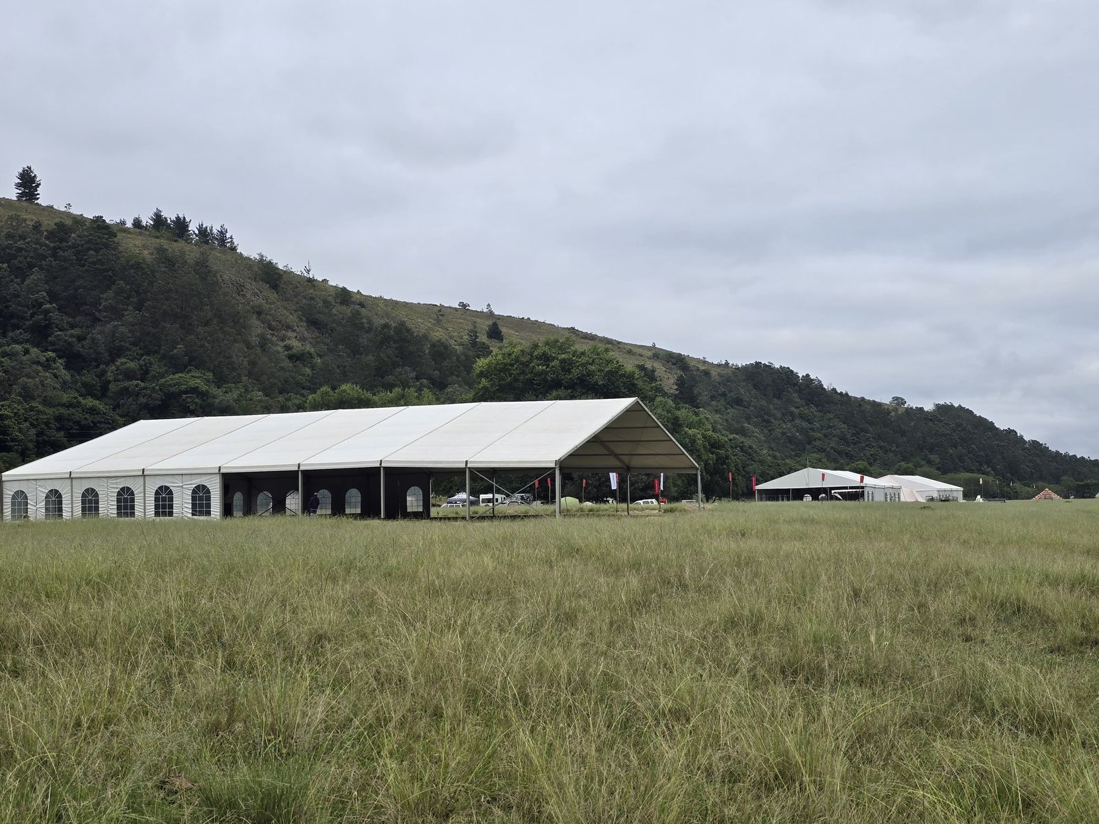 Large marquee tent in green field with mountain backdrop — corporate event Gauteng